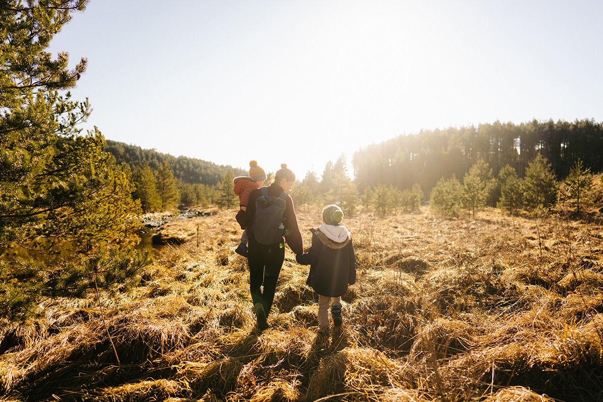 Anya két gyerekkel az őszi tájban sétál
