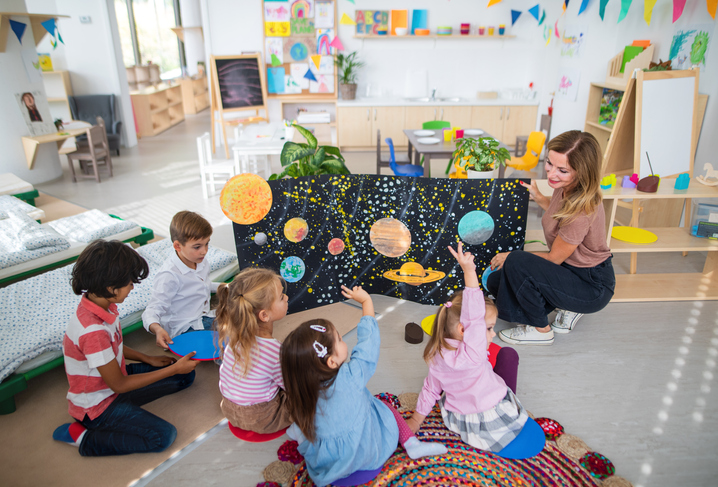 Montessori osztályteremben a földön körben ülő kisgyerekek pedagógusukkal