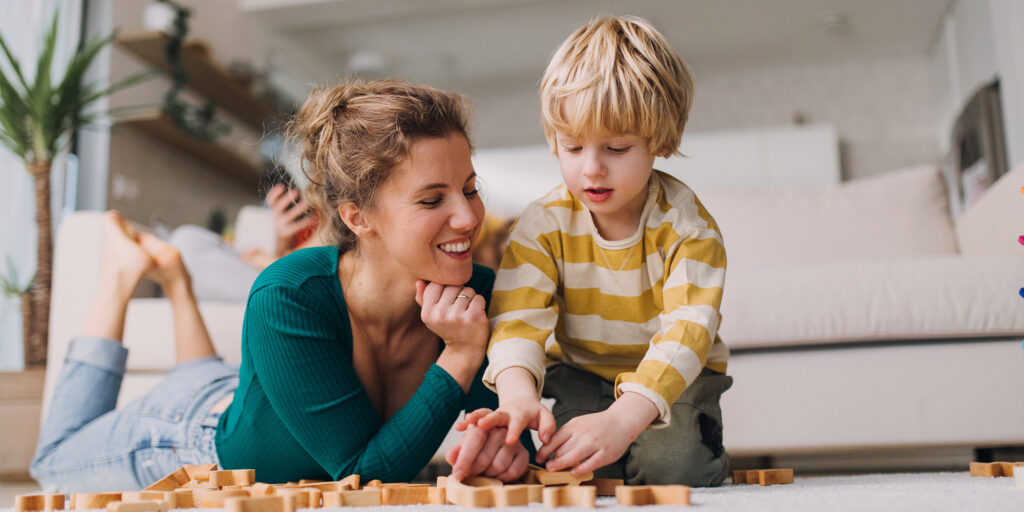 Mami kisfiát figyeli aki a Montessori módszer ajánlásai szerint játszik játékával